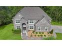 An aerial view of gray brick two-story house, showcases a well-manicured lawn and mature surrounding trees at 3206 Letha Woods Dr, Conyers, GA 30094