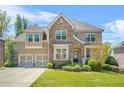 Charming two-story brick and stone home with a well-manicured lawn and a two-car garage at 5895 Springbox Dr, Suwanee, GA 30024