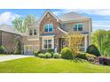 Beautiful two-story home featuring a brick and stone exterior, a well-maintained lawn, and a two-car garage at 5895 Springbox Dr, Suwanee, GA 30024