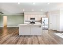 Modern kitchen with white cabinets, stainless steel appliances, island with sink, and luxury vinyl plank flooring at 2959 Rambler Dr, Loganville, GA 30052