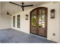 Inviting front porch featuring ceiling fans and a beautiful arched wood entry door at 9315 Prestwick Club Dr, Johns Creek, GA 30097