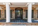Covered front porch with white columns, brick accents, and a black front door with sidelights at 6141 Windsong Way, Smoke Rise, GA 30087