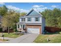 View of a two-story home with a blue-accented gable, attached garage, and landscaped front yard at 327 Morning Frost, Canton, GA 30114