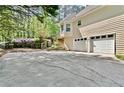 Attached two-car garage with a large driveway and view of the backyard and wooded area at 1315 Pembridge Nw Way, Kennesaw, GA 30152