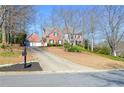 Charming two-story brick home with a long driveway and manicured lawn in a sunny neighborhood at 6450 Oak Valley Dr, Cumming, GA 30040