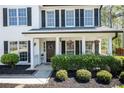 The front porch has a dark door, a nice wreath, and two beautiful hanging plants, surrounded by manicured shrubs at 12495 Concord Hall Dr, Alpharetta, GA 30005
