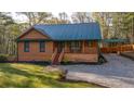 Attractive house featuring wood siding, a green metal roof, front porch, and long gravel driveway at 5070 Smithfield Rd, Bowdon, GA 30108