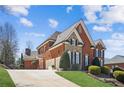 Stunning brick home featuring a stone accent, attached garage, well manicured lawn, and a concrete driveway at 5945 Boulder Bluff Dr, Cumming, GA 30040