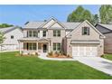 Beautiful new construction home featuring a brick and siding exterior, lush lawn, and a two-car garage at 5816 Creek Indian Dr, Sugar Hill, GA 30518