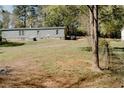 Home with a spacious backyard, featuring a partial fence and mature trees in the background at 153 Helen Rd, Covington, GA 30016
