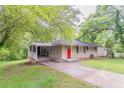 Inviting single-story home featuring a covered carport, manicured lawn, and an eye-catching red front door at 2304 Ousley Ct, Decatur, GA 30032