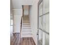 Bright entryway with hardwood floors, a white door, staircase with carpet runner, and gray painted trim at 2378 Morgan Creek Rd, Buford, GA 30519