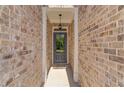 Front door in a recessed entryway with brick walls, a hanging light, and a 'welcome' mat at 2378 Morgan Creek Rd, Buford, GA 30519