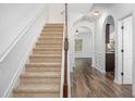 Inviting foyer with a carpeted staircase and hardwood flooring, enhanced by archway details at 3095 Bonnes Dr, Lithonia, GA 30038