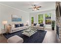 Bright living room with a stone fireplace, ceiling fan, and large windows overlooking the yard at 682 Shelton Sw Ave, Atlanta, GA 30310