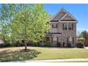 Attractive two-story brick home featuring a well-kept lawn and mature trees, offering a serene and picturesque setting at 6150 Birchfield Trl, Cumming, GA 30041
