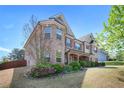 A beautiful two-story brick home, showcasing its well-maintained lawn and colorful flower beds under a bright blue sky at 6150 Birchfield Trl, Cumming, GA 30041