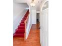 Home entryway featuring hardwood floors, a staircase with red steps, and natural light from the door at 1294 Park Pass Way, Suwanee, GA 30024
