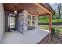 Inviting covered front porch featuring stone pillars, wood beam accents, and stylish pendant lighting at 1002 Coleman Sw St, Atlanta, GA 30310