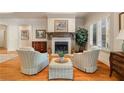 Cozy living room with fireplace, comfortable seating, and a view of the outdoors through shuttered windows at 2550 Ballantrae Cir, Cumming, GA 30041