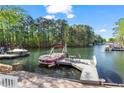 Lakeside view featuring a boat tied to a private dock with seating, perfect for enjoying the water at 6360 Spinnaker Ln, Alpharetta, GA 30005
