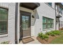 Charming front door with a 'Welcome' mat, painted brick, and modern exterior light fixture at 2424 Lakeshore Se Ln, Atlanta, GA 30316