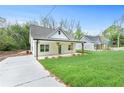 Well-manicured front yard and long driveway leading to a quaint, single-story home with a covered porch at 5232 W Mountain St, Stone Mountain, GA 30083