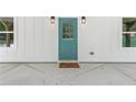 Close-up of the teal front door, framed by white siding and symmetrical windows at 5232 W Mountain St, Stone Mountain, GA 30083