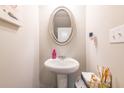 Stylish powder room featuring a pedestal sink, elegant mirror, and modern fixtures at 7144 Gladstone Cir, Stonecrest, GA 30038