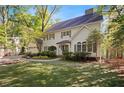 Inviting two-story home with green lawn, brick driveway and lush trees offering curb appeal and a welcoming ambiance at 4477 Jett Nw Rd, Atlanta, GA 30327