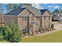 Charming brick home with attached garage, lush landscaping, and gray roof at 4580 Cloister Cir, Hampton, GA 30228