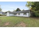 A sprawling front yard with a one-story home featuring vinyl siding, black shutters, and an attached garage at 175 Cypress Dr, Covington, GA 30016