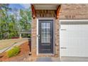 Up close, brick townhome featuring a front door with glass panes and a white garage door, and wooden supports above door at 2042 Clay Rd, Snellville, GA 30078