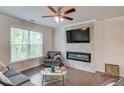 A cozy living room with a fireplace, hardwood floors, large windows, a ceiling fan, and neutral paint at 2042 Clay Rd, Snellville, GA 30078