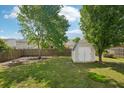 Backyard with green grass, a wooden fence, mature trees, a storage shed and a fire pit at 5450 Fieldfreen Dr, Cumming, GA 30028