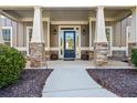 Inviting front porch with stone accents, columns, and a stylish glass door at 1041 Sweetwater Bridge Cir, Douglasville, GA 30134