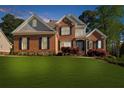 A classic red brick home with black shutters, a manicured lawn, and mature trees at 6252 Fernstone Trl, Acworth, GA 30101
