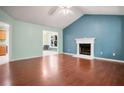 Cozy living room featuring hardwood floors, vaulted ceiling, and white-mantled fireplace at 11268 Flat Shoals Rd, Covington, GA 30016
