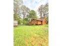 Backyard of the house with some trees and foliage. Grass is overgrown and unkempt at 1445 Diplomat Dr, Riverdale, GA 30296
