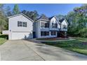 Charming two-story home with light siding, dark shutters, front yard, long driveway and an attached garage at 3211 Thompson Mill Rd, Buford, GA 30519