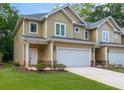 View of townhouse showcasing the attached garage, well-maintained lawn, and desirable neighborhood at 6860 Robinson St, Lithonia, GA 30058
