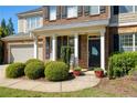 Charming front porch with brick and shingle accents, decorative shrubs, and red potted plants framing the doorway at 5075 Chase Ln, Cumming, GA 30040