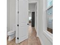 Bright hallway view featuring wood-look flooring and a glimpse into an adjacent powder room at 683 Summitt Hill Way, Cumming, GA 30040