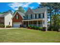 Lovely two-story home with a covered front porch, brick accents, and a lush green lawn in a neighborhood setting at 1052 Secret Ne Trl, Sugar Hill, GA 30518