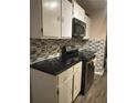 A kitchen with white cabinets, dark countertops, stainless steel appliances, and mosaic tile backsplash at 1081 Singleton Valley Cir, Norcross, GA 30093