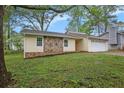 Well-kept single story home with a two car garage, rock facade, and well manicured lawn at 1248 Reilly Ln, Clarkston, GA 30021