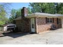 Brick home featuring a detached garage and an exterior access door, with a chair in the yard at 1646 Hurt Sw Rd, Marietta, GA 30008
