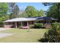 Charming brick home featuring a well-maintained lawn, inviting curb appeal, and vibrant flowering bushes at 1646 Hurt Sw Rd, Marietta, GA 30008