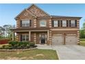 Charming brick home with a covered porch, two-car garage, and manicured front yard landscaping at 811 Holly Mist Ct, Loganville, GA 30052