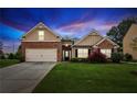 Charming single-Gathering home featuring a brick facade, well-manicured lawn, and an attached two-car garage at dusk at 4580 Orchard Ridge Ct, Cumming, GA 30028